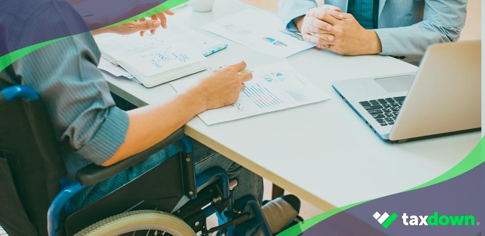 Persona discapacitada en silla de ruedas consultando beneficios fiscales.