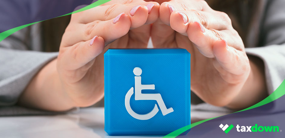 Manos protegiendo un símbolo de persona con silla de ruedas