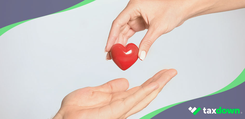 Persona dando un corazon de plástico rojo a otra representando una donación que podría ser desgravada.
