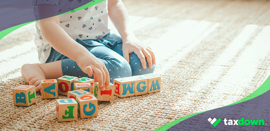 Niño jugando con cubos con letras por el que se podrían tener beneficios fiscales